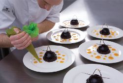 Piping Bags Comfort Green bag being used to add decorative dots of sauce for plating up a dessert.